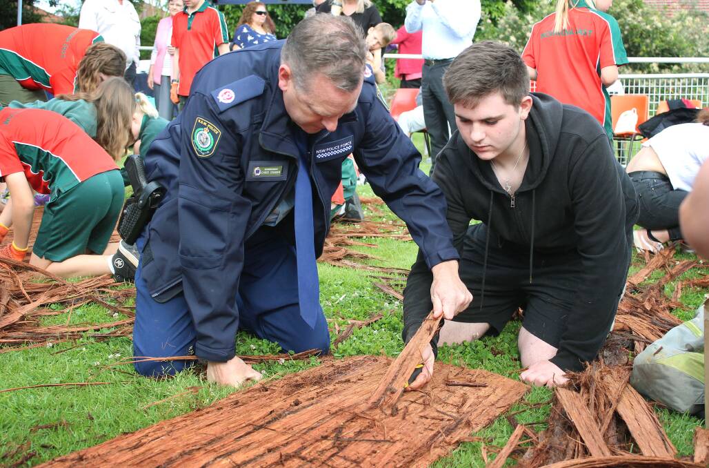Working together: Acting Assistant Commissioner Chris Craner stripped bark off wood with a PCYC participant to help build a canoe. He launched a new police program that aims to build relationships with Aboriginal teens. Picture: Ashleigh Tullis