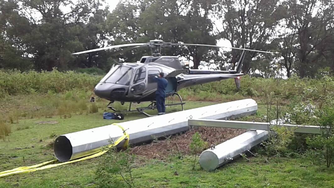 Heavy load: A helicopter landed at the temporary helipad in Mount Pleasant before transporting a power pole to the Mount Keira Summit Park on Tuesday.