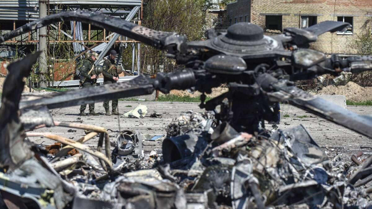 Ukrainian servicemen survey the remains of a Russian helicopter at the Gostomel airfield near Kyiv on Thursday. Picture: EPA