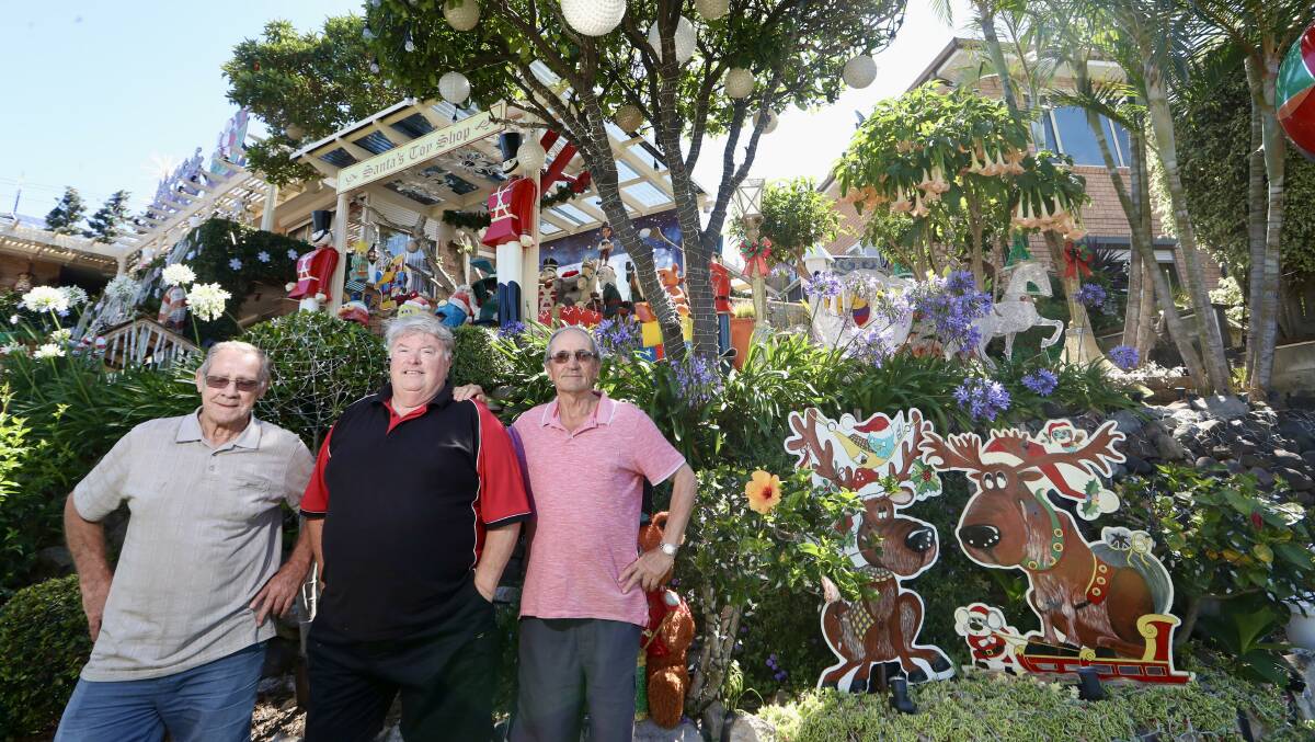 Christmas lights wizard Craig Hughe in front of his Mount Warrigal home with his friends and co-workers Rick Dawes and Cane Petkovski. Picture by Sylvia Liber