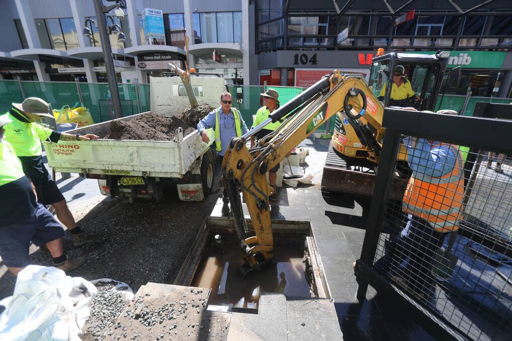 Going down with a fight: Ripping out the roots of Crown Street Mall's gum trees caused havoc on Thursday, as council crews burst a water pipe. Picture: Robert Peet.