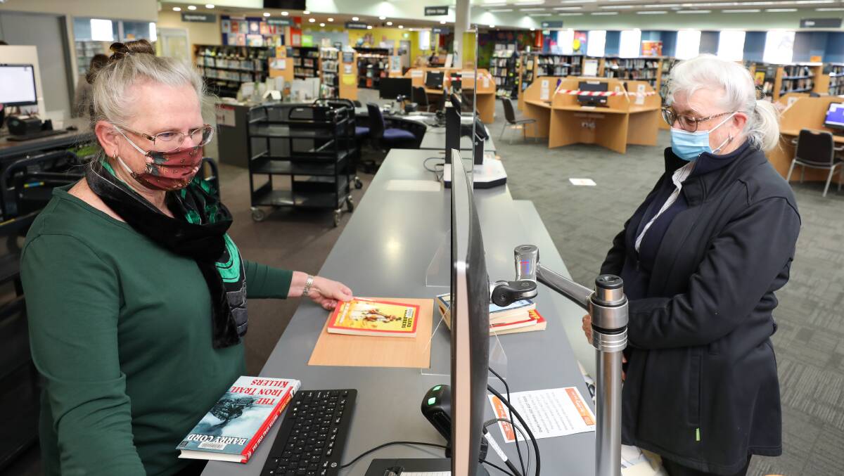 Sandra Rock (left) with customer Sharon Langley borrowing books for her 92-year-old father. 