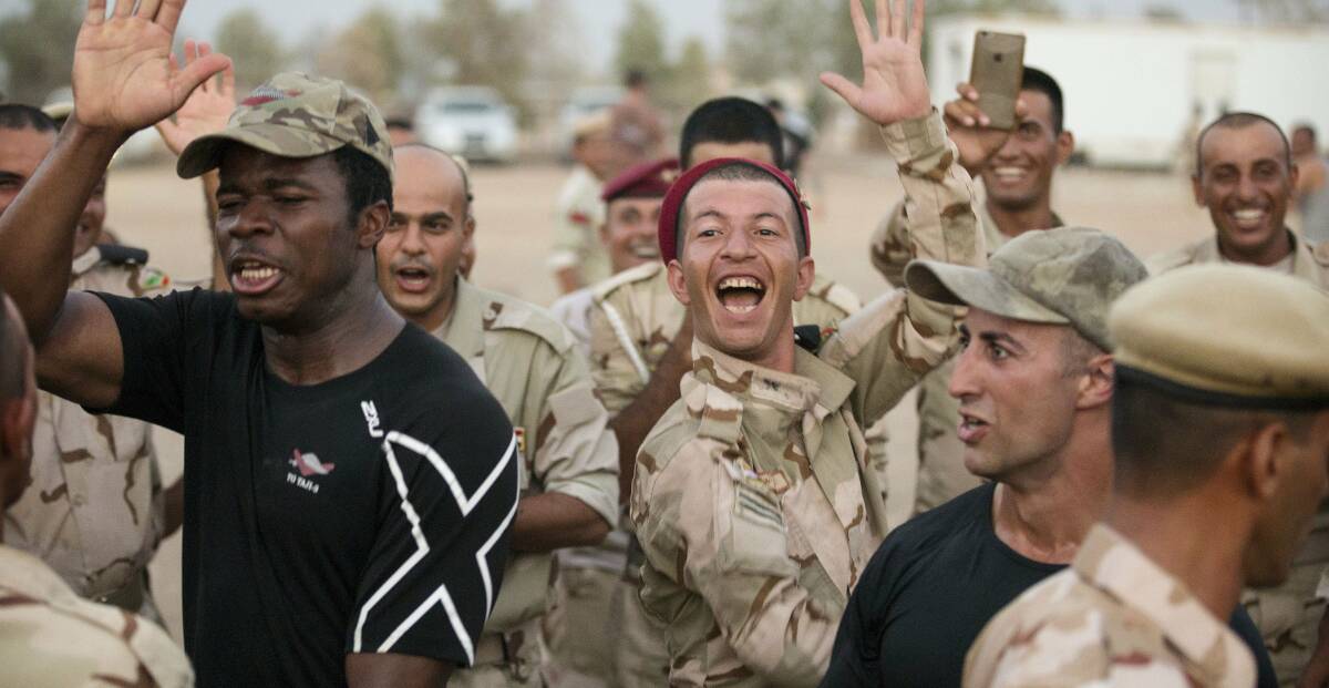 War games: Pte Bukasa and Corporal Stefan Pitruzzello join Iraqi Army soldiers in a celebratory dance. Pictures: supplied by the Australian Army.