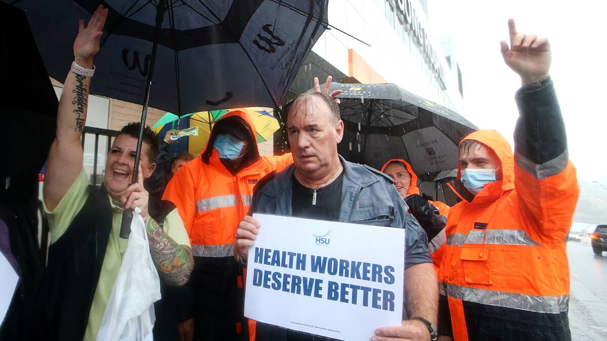 Strong resolve: HSU members in Wollongong braved the downpour, unanimously voting to continue their industrial action until the NSW Government agrees to change their wages policy. Pictures: Sylvia Liber.