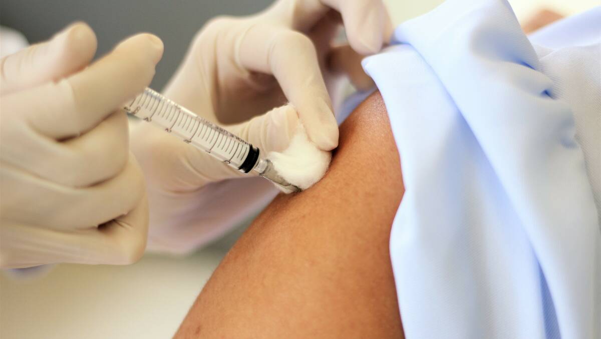 A person receives a needle in their upper arm. Picture by Shutterstock