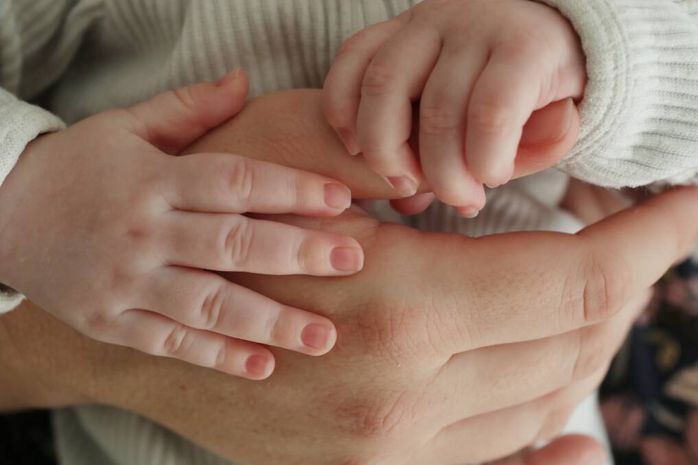 Six-month-old Oliver's hands grip on to his mum, Lauren's thumb. The Caldewood woman has a nurse come to do weekly exercises to help her bond with her second son, after a traumatic birth in January. Picture by Robert Peet.
