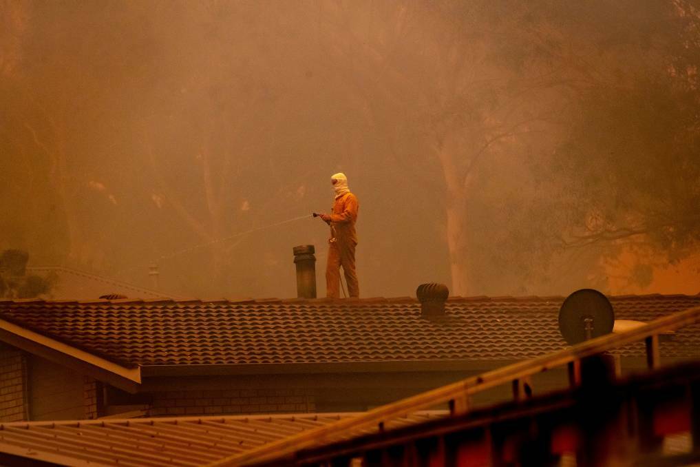 Residents on Murramarang Rd in Bawley Point hosed their roofs as a bushfire threatened on Thursday afternoon. Picture: Sitthixay Ditthavong