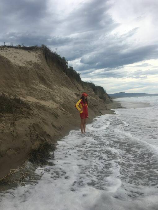 MASSIVE DAMAGE: A surf lifesaver in front of the massive erosion on Seven Mile Beach at Shoalhaven Heads. Image supplied