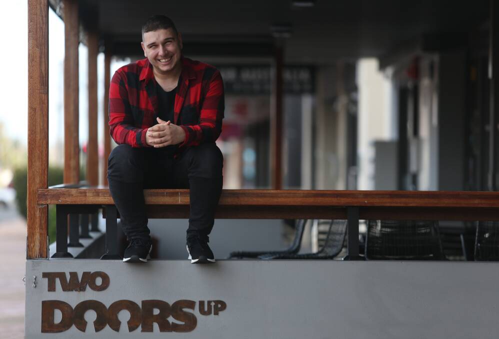Jamal Abdul sitting on the fence of Two Doors Up Cafe in Corrimal. Picture by Robert Peet.