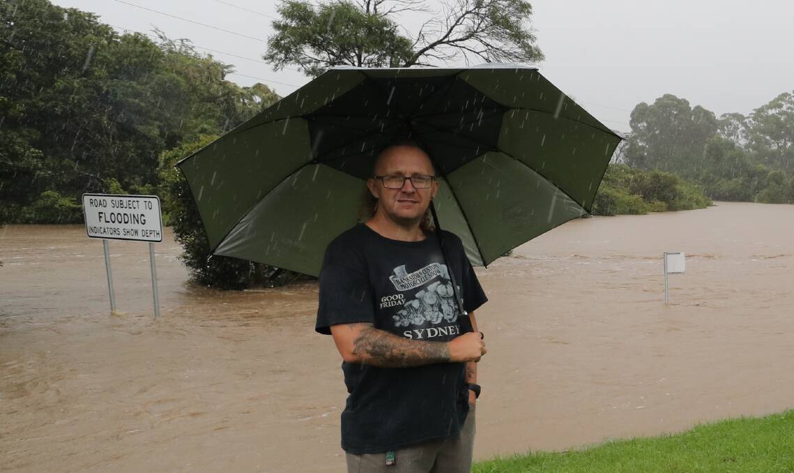 Wayne Haines watches Mullet Creek break its banks at Kanahooka on April 7. Picture: Robert Peet