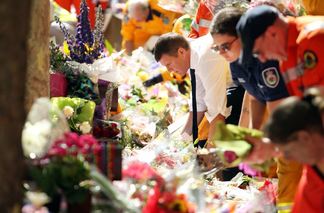 Flashback to 2014, with then-premier Mike Baird joining with volunteers from the SES, RFS and Red Cross to remove flowers and other tributes for Lindt Cafe siege victims Tori Johnson and Katrina Dawson. AMC file image by Max Mason-Hubers.