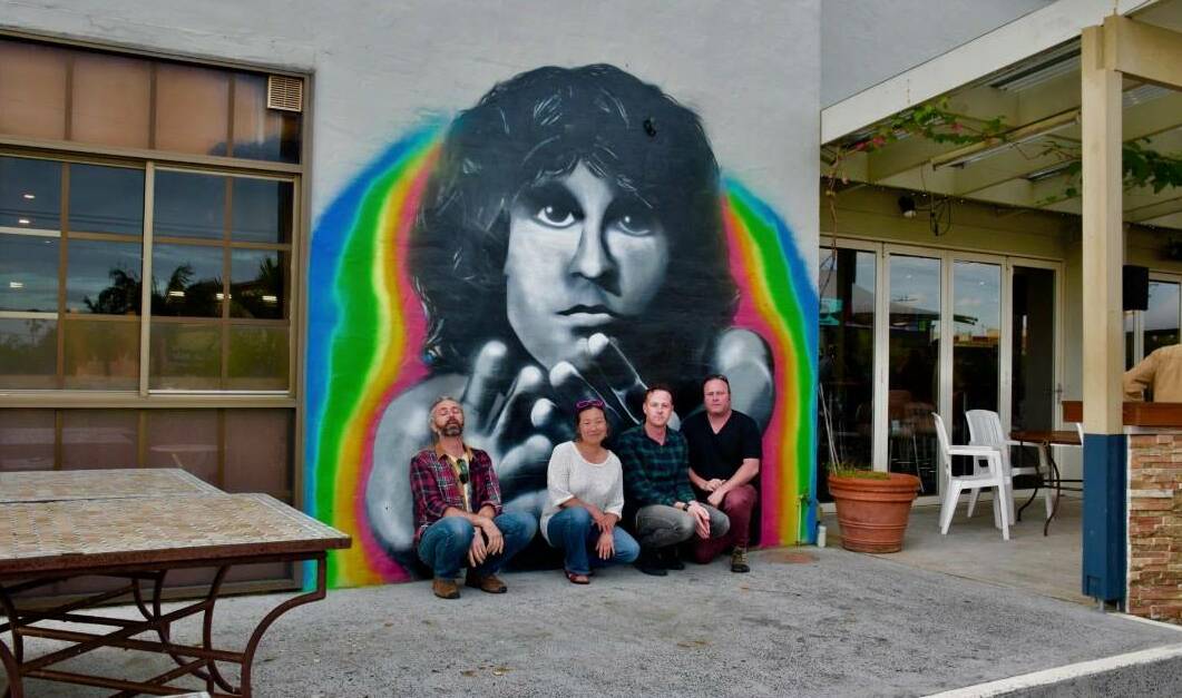 Rich Mikic (left) and band members from Unlocking The Doors - in front of the new mural created to honour the late Jim Morrison, on the side of Beaches Hotel in Thirroul. Picture: Facebook