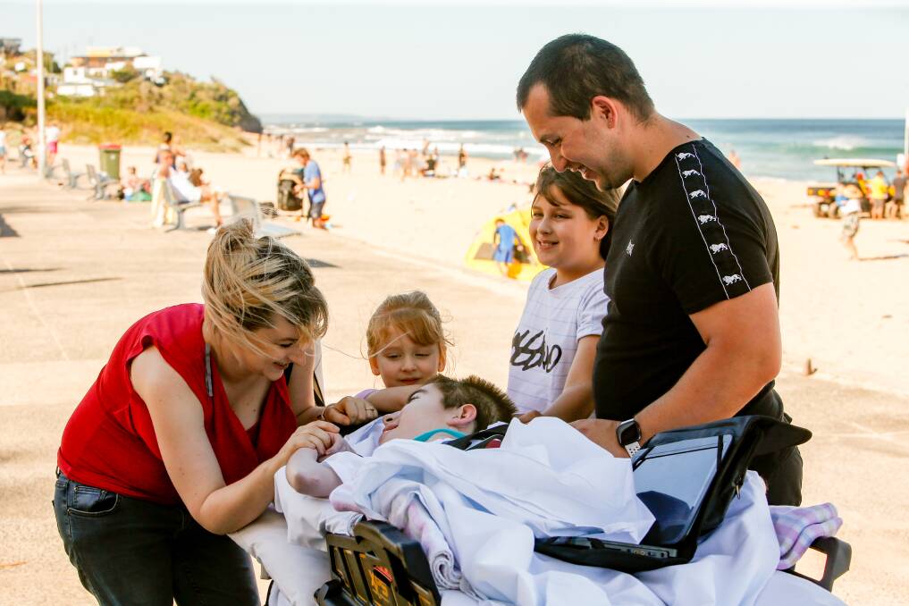 EARLY CHRISTMAS PRESENT: Jayde Jordan and Jayson Guido with their children Levi, Olivia and Sophia at Thirroul Beach on Sunday, made possible by the Starlight Foundation. Picture: Anna Warr