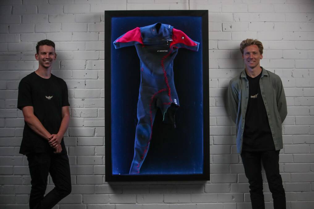 Shark attack survivor Brett Connellan (right) with the wetsuit he was using when attacked at Bombo beach in 2016. He and film maker Sam Tolhurst have created a movie about his attack and recovery. Picture by Adam McLean.