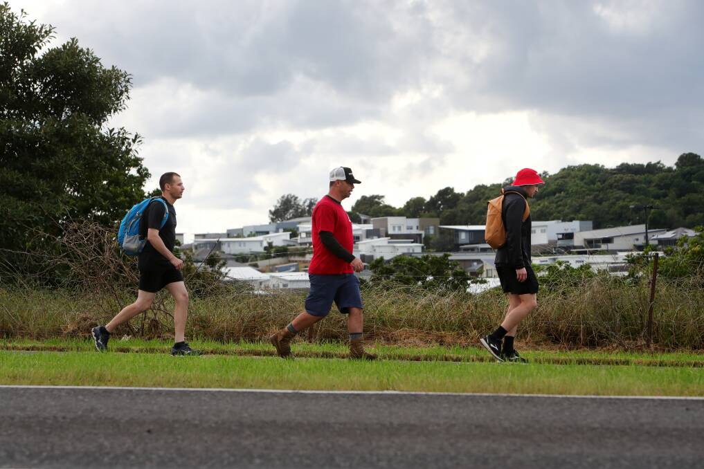 Andrew Horne (middle) with Anthony Jenkins and Harisson Freud walking along Dunmore Road on their way to Kiama, after walking 103 kilometres from charity. Picture: Sylvia Liber