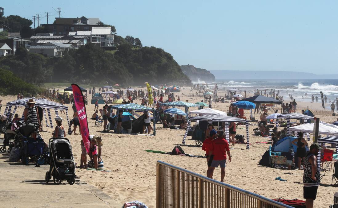 Hoards of people pack Thirroul Beach on Sunday morning as the temperature heats up and Nippers at the surf club resumes. Picture by Robert Peet.