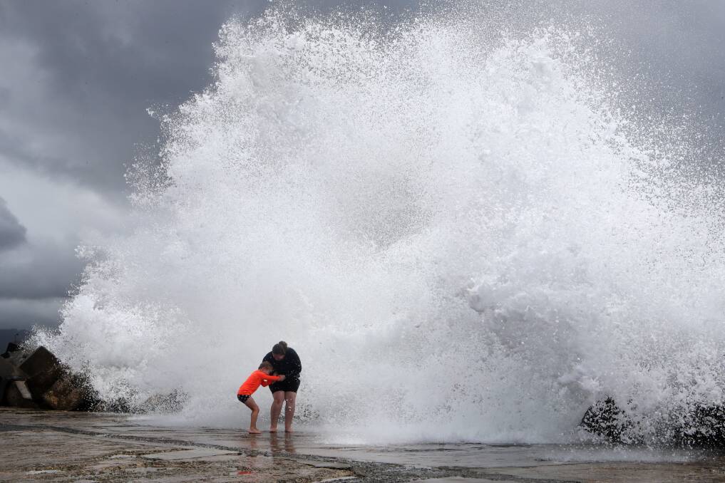 RISKY BUSINESS: People play in the giant seaspray at Wollongong breakwall near the lighthouse on Wednesday. Picture: Sylvia Liber