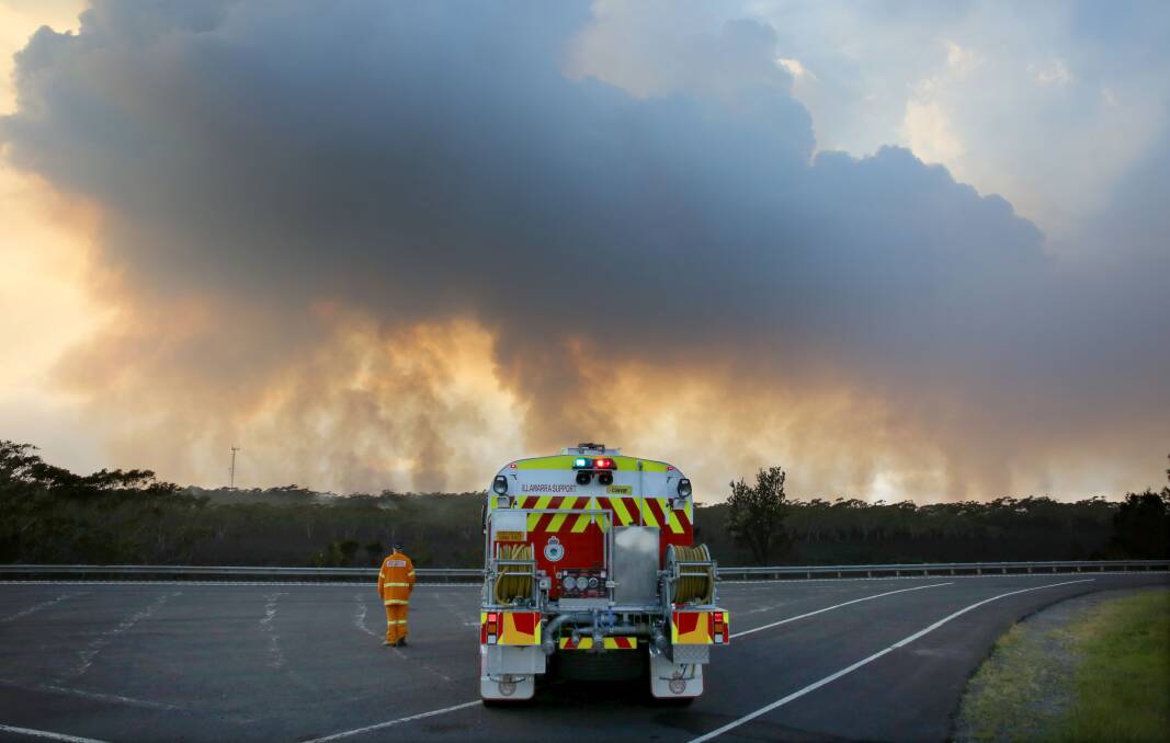 FLASHBACK: A Rural Fire Service volunteer stands beside his tanker on the M1 watching a bushfire still burning on Maddens Plains in December 2015. Picture: Kirk Gilmour