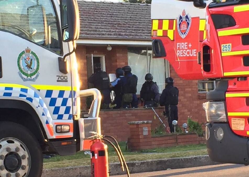 Police break down the door of a unit on the Princes Highway at West Wollongong after a stand-off on Tuesday. Picture: Illawarra Mercury