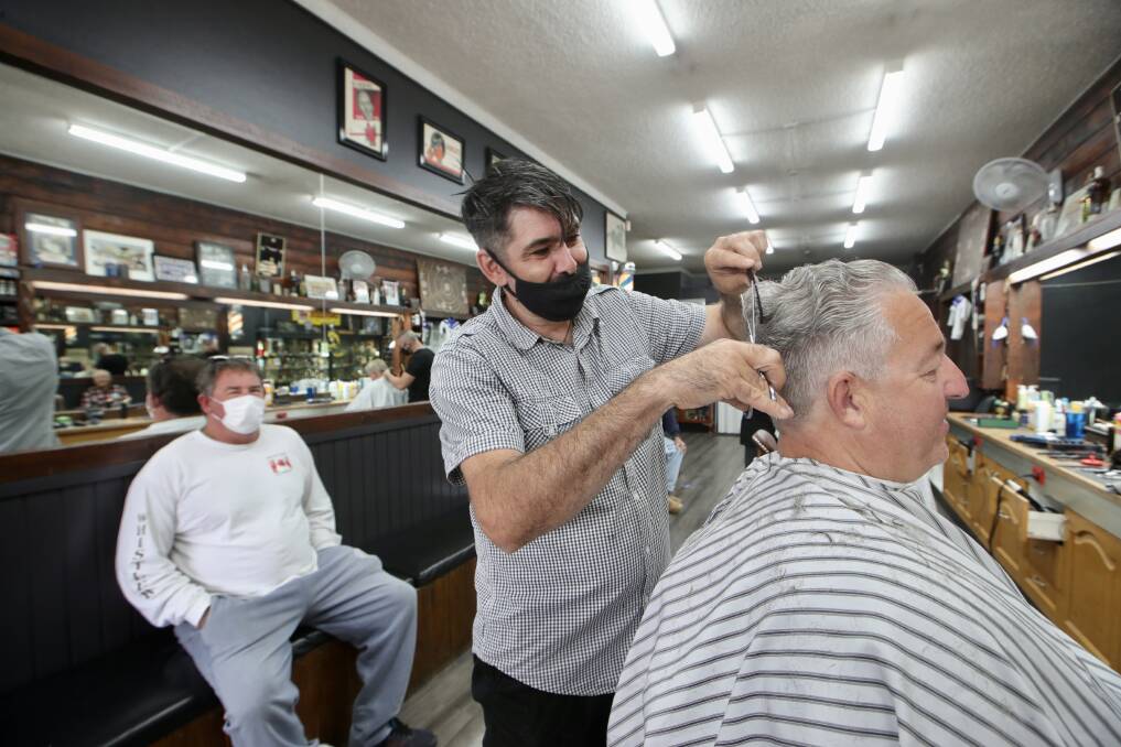 Michael Paule from Pauley's Barber Shop shop in Warilla gives long-time client Greg Porter a hair cut on Monday. Picture: Sylvia Liber
