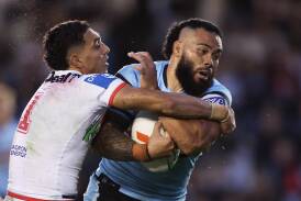 Tyrell Sloan (left) drags down Sharks wrecking ball Siosifa Talakai on Sunday. Picture Getty Images 