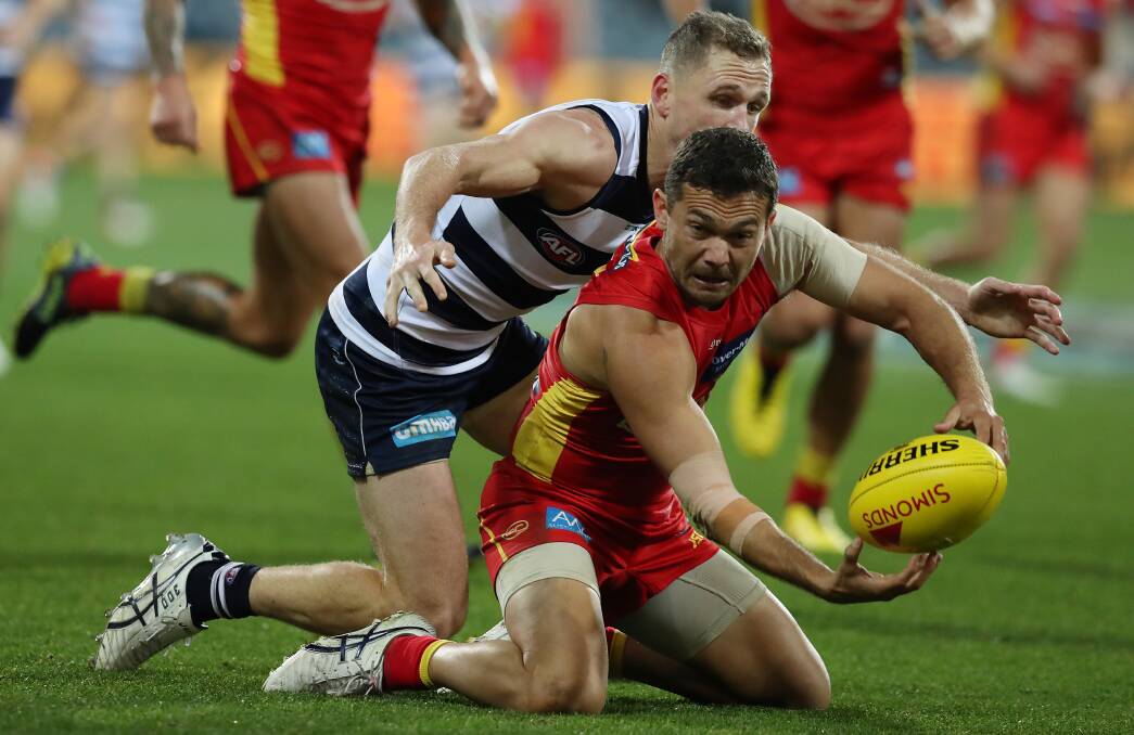 Closing in: Gold Coast's Jarrod Harbrow handballs as he is tackled by Joel Selwood on Saturday. Picture: Graham Denholm/AFL Photos via Getty Images