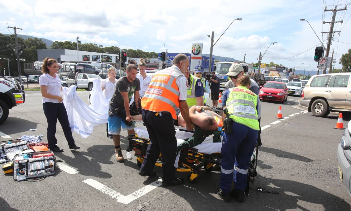 NSW Ambulance paramedics wheel the injured man towards an ambulance. Picture: Robert Peet