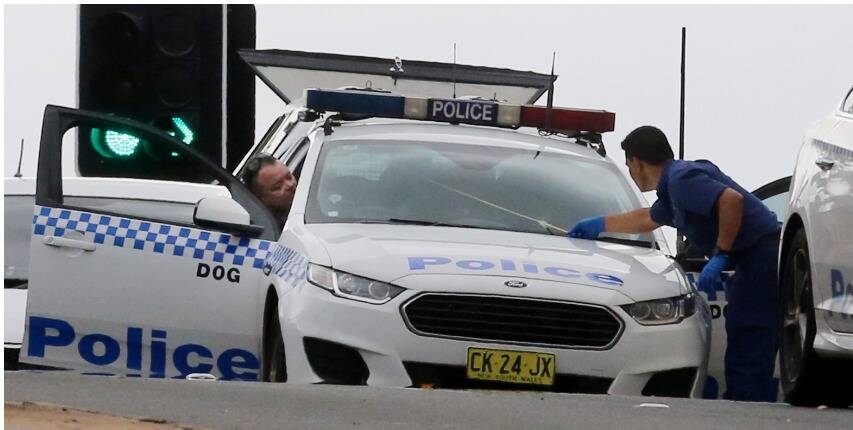 Police examine a bullet hole made in the windscreen of a passing police car. Picture: Robert Peet 