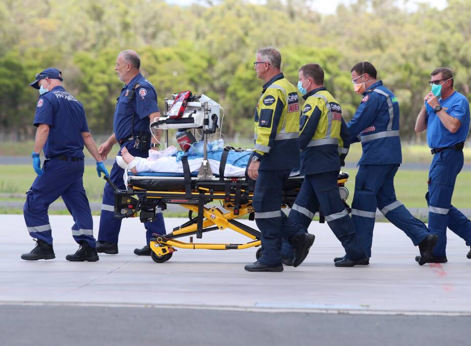 The injured man is led towards a Careflight helicopter at Shellharbour Airport. Picture: Sylvia Liber 