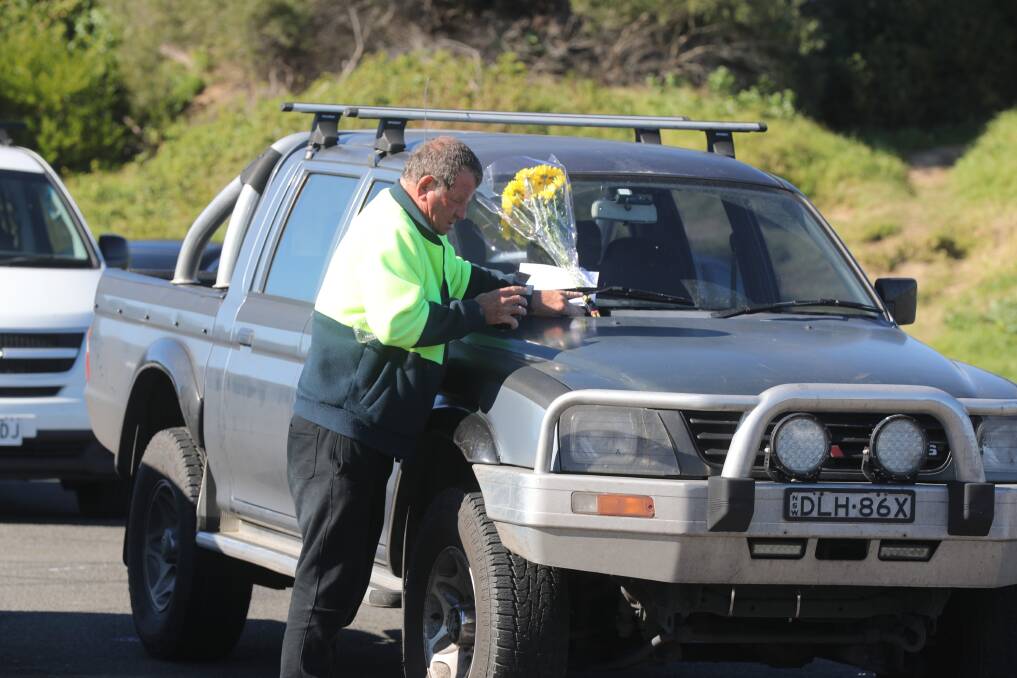 Michael Beck leaves a floral tribute on the deceased men's car at Bellambi boat ramp. Picture: Robert Peet 