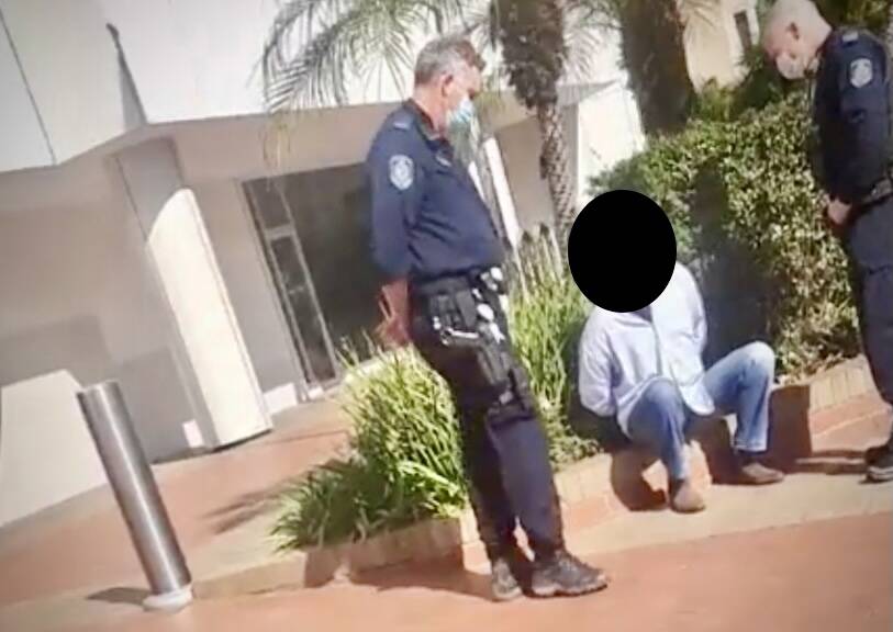 A man is seen in police custody in a scene from video at Tuesday's event. 