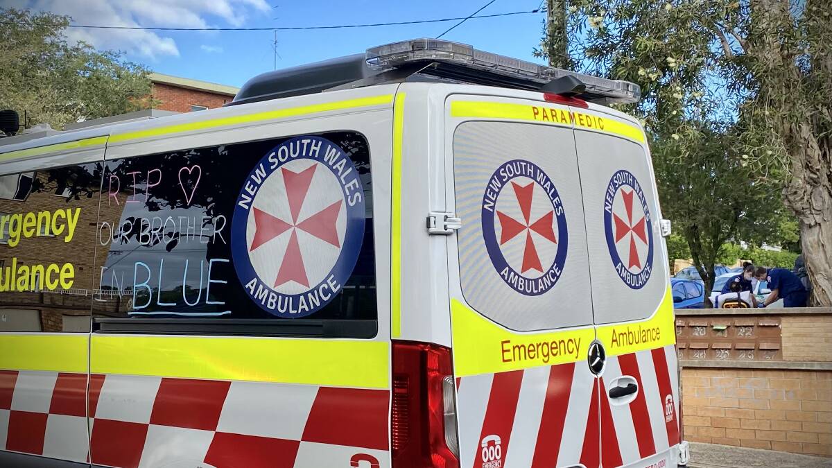 Paramedics with a tribute to murdered colleague Steven Tougher in their window attend a job on Smith St, Wollongong, on Tuesday morning. 