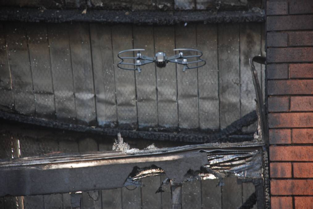 A drone takes a look through one of the home's charred window frames. Picture: Angela Thompson 