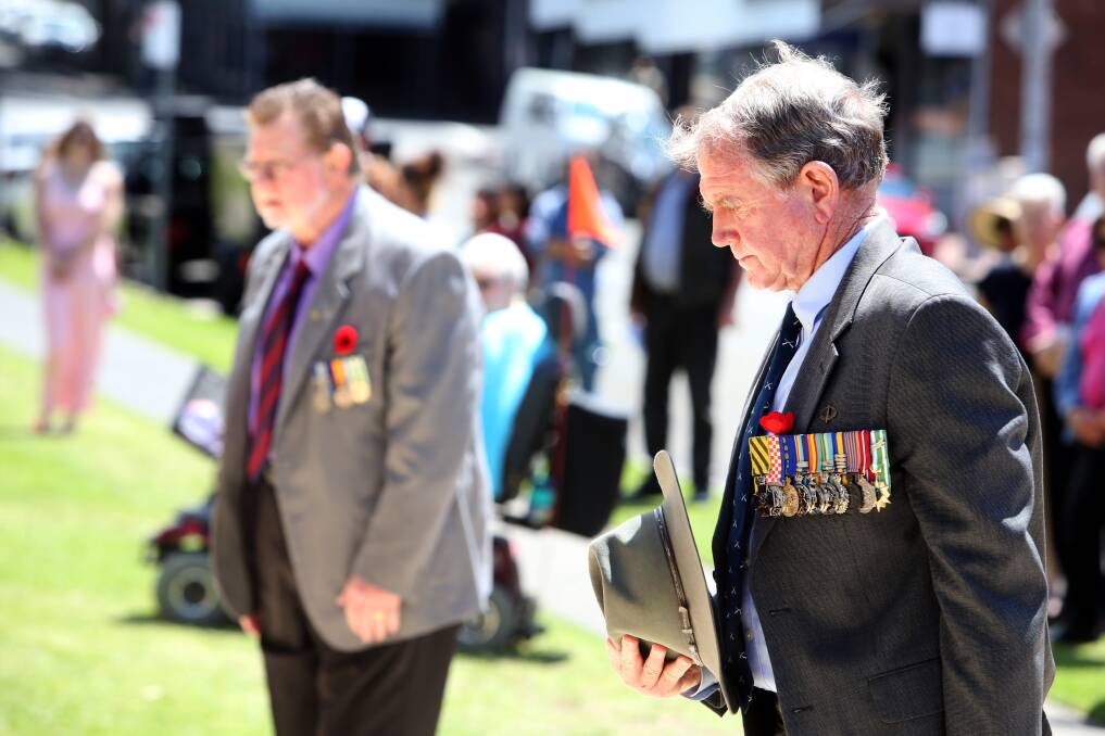 HATS OFF: Men pay their respects at the service, led by speakers including Royal Australian Navy Captain Stuart Dunne and Wollongong RSL president Peter Poulton (below). 