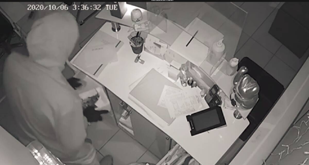 A gloved figure is captured in security camera footage from HL Nail Salon in Albion Park. 