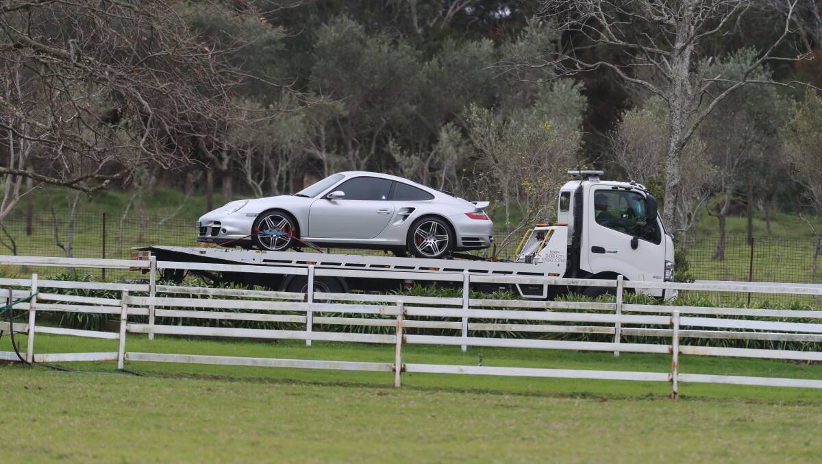 A silver Porsche departs the Walker St property on the back of a car carrier on Wednesday. Picture: Robert Peet 