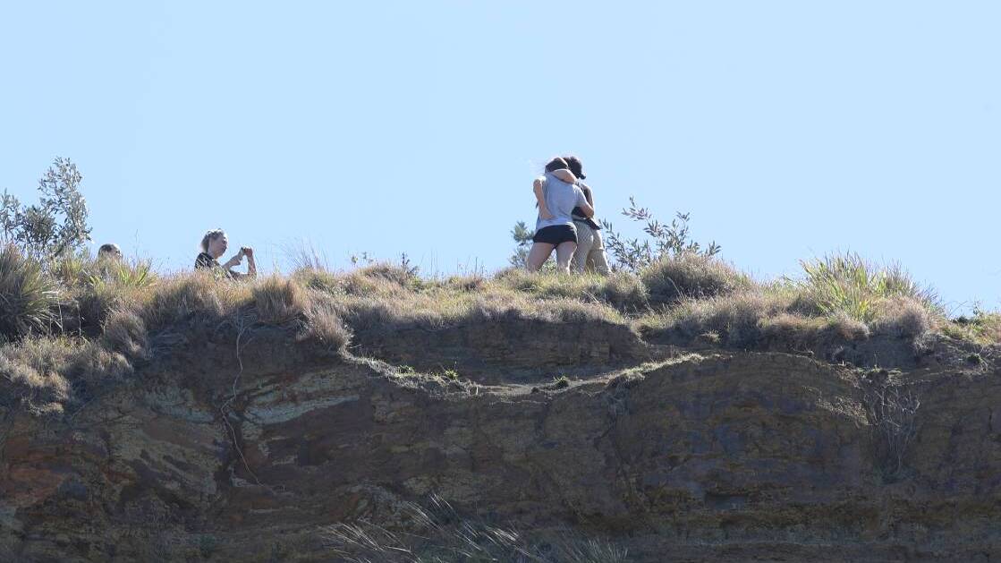Climbers pose for a picture on the cliff ledge, the day after a man plumetted to his death at the site in September 2018. Picture: Adam McLean