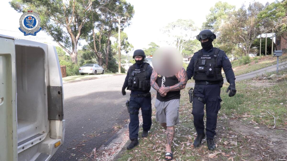 The alleged sergeant-at-arms is led towards a police car at Mollymook, Wednesday morning. Picture: NSW Police 
