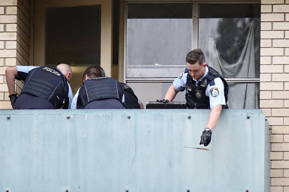 A police officer drops a knife from the third-floor balcony. Picture: Adam McLean 