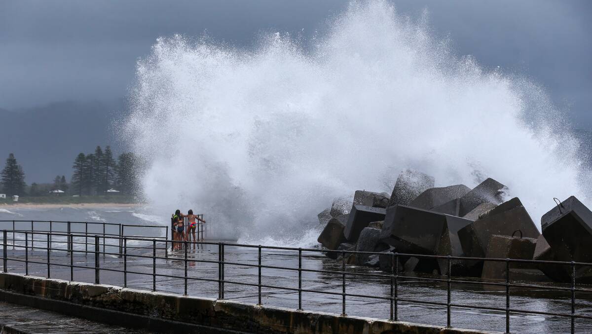 Kids facing the storm at the break wall at Wollongong Harbour. Picture: Wesley Lonergan