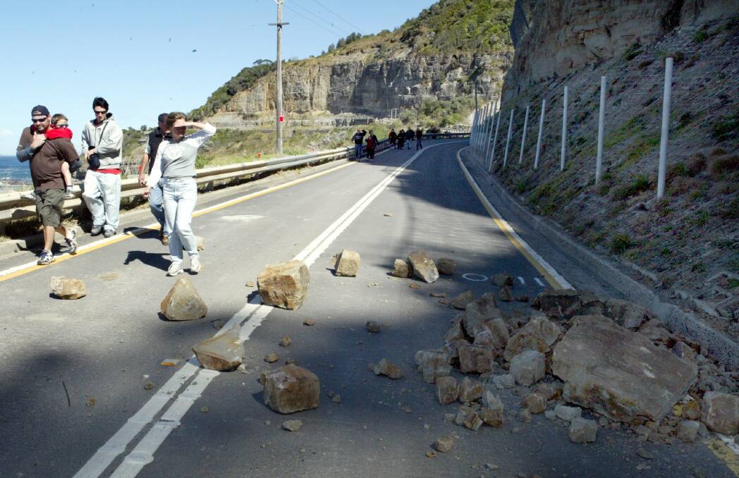 Point taken: In 2003 residents walked past barriers at Lawrence Hargrave Drive to protest the closure - just minutes before a rockfall that really proved why the road was closed. Picture: Robert Peet