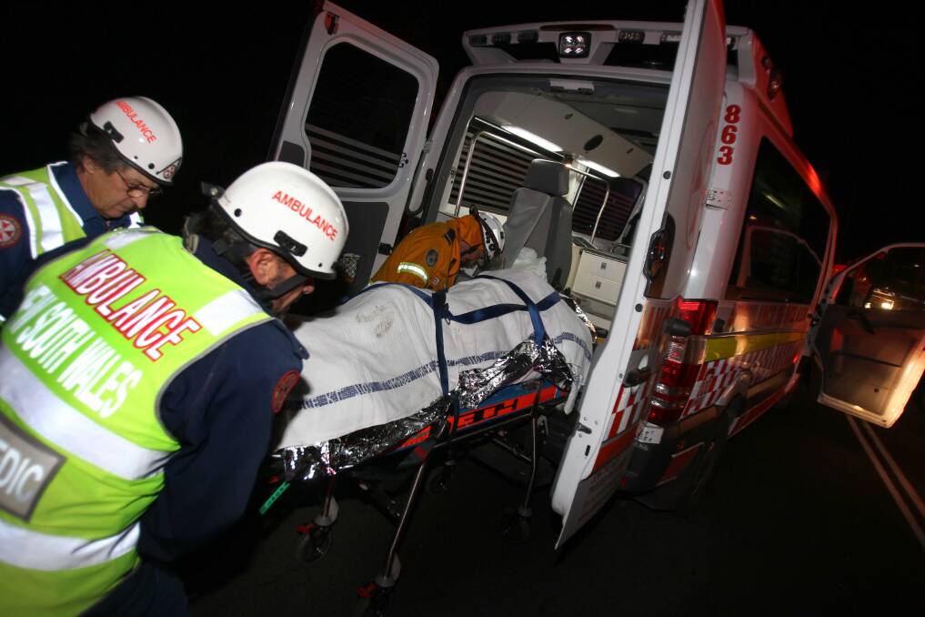 Aftermath: Rescue workers remove the injured from the tour bus which careered down Barrengarry Mountain with 28 passengers aboard.