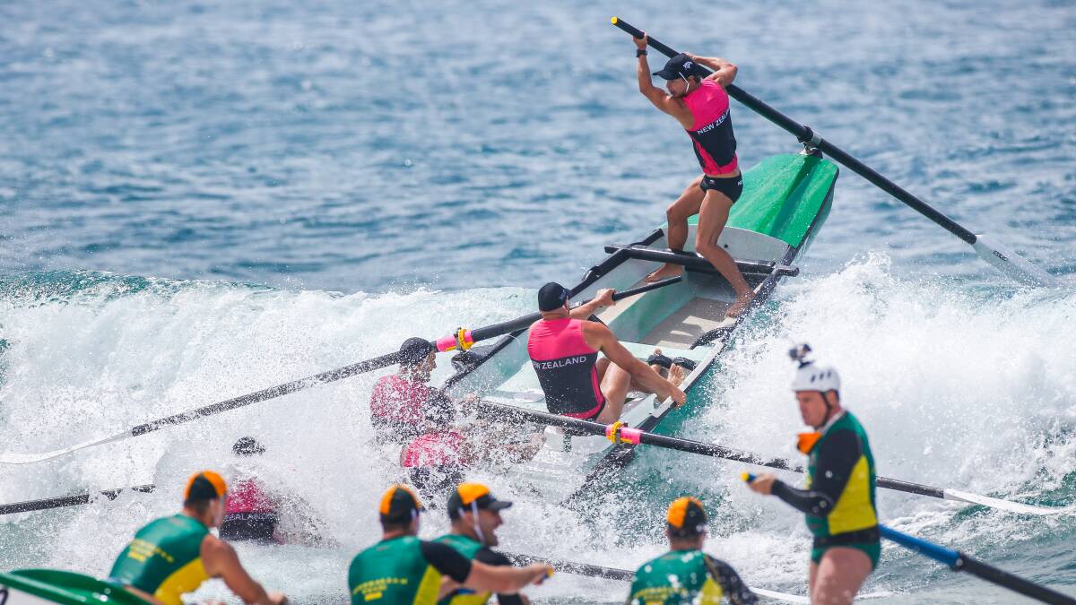 Riding high: A New Zealand crew are up-ended in demanding conditions at last year's Navy Surf Rowers League at Shellharbour Beach. Picture: Adam McLean
