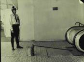 A policeman stands near Wilhelmina Kruger's mop and bucket at Piccadilly, where it was left after an unknown assailant dragged her down the escalator and into the car park before murdering her.