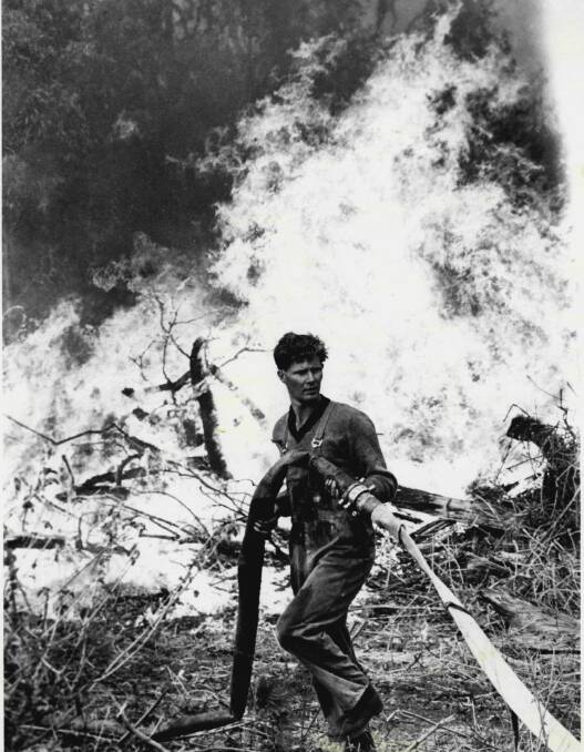 A fire fighter prepares to pour water onto a fire burning in Gahans Avenue, Woonona, in October 1968.