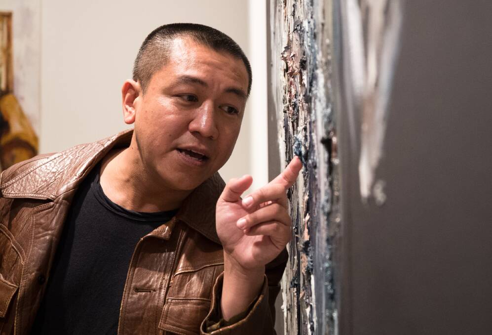 Anh Do points out three hidden fake diamonds in his portrait of Jack Charles (representing the portion of Jack's life as a cat burglar), at the Art Gallery of NSW in Sydney on Wednesday. Picture: Janie Barrett