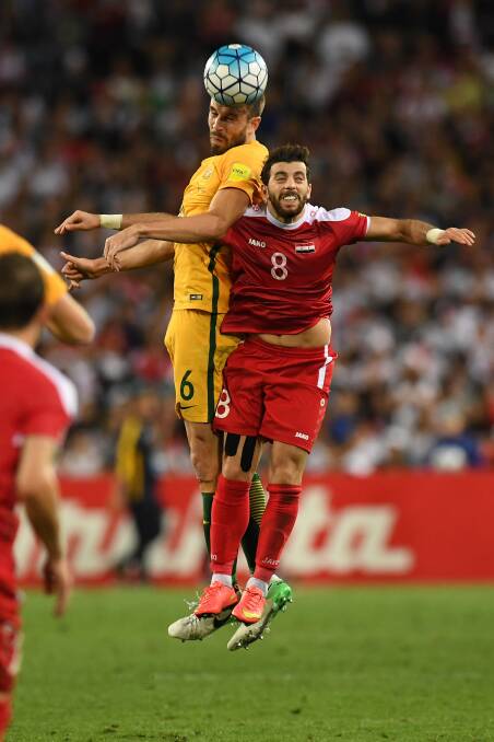 UP FOR IT: Dapto's own Socceroos defender Matt Jurman heads the ball against Syria. Picture: AAP