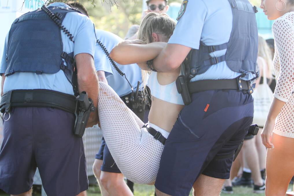 A woman is being escorted out of the Corona SunSets festival at North Wollongong beach on Saturday. Picture: Adam McLean