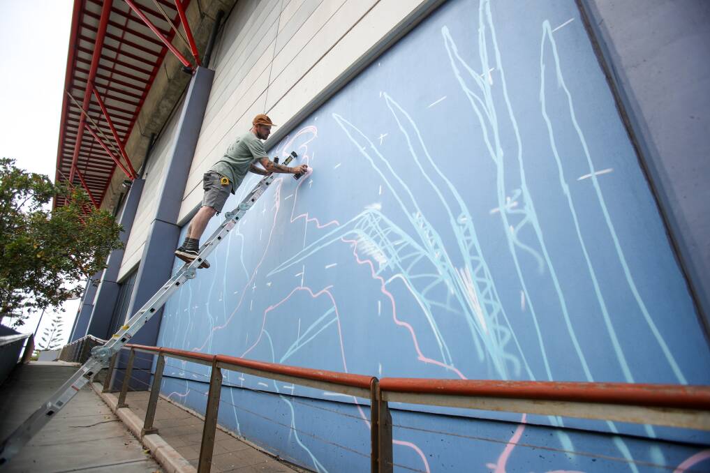 Aerosol artist Sion Gruffydd creating the base work for one of several large murals on the outside of WIN Entertainment Centre. Picture: Adam McLean
