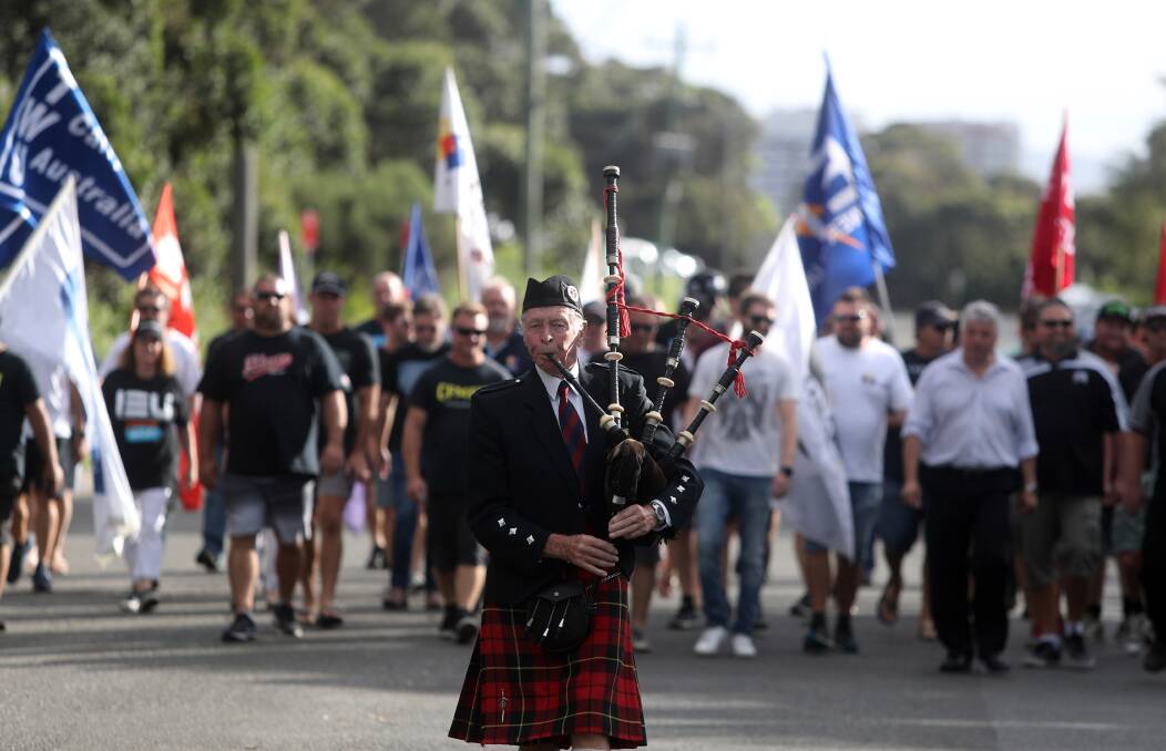 SIGH OF RELIEF: A bag piper plays as Port Kembla Coal Terminal workers marched back to work on Tuesday. Picture: Robert Peet